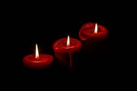 3 rote Kerzen im Dunkeln